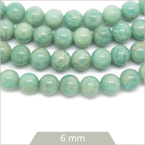 Perles rondes d'Amazonite vert d'eau, 6 mm, de la marque perlesatoutva, disposées en rangée sur une surface claire.